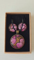 Handgefertigtes Schmuckset Solas Aurora mit rundem Anhänger und passenden Ohrringen in Rosa-, Magenta- und Goldtönen mit fliessendem Marmoreffekt unter Glas.