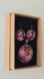 Handgefertigtes Schmuckset Solas Aurora mit rundem Anhänger und passenden Ohrringen in Rosa-, Magenta- und Goldtönen mit fliessendem Marmoreffekt unter Glas.