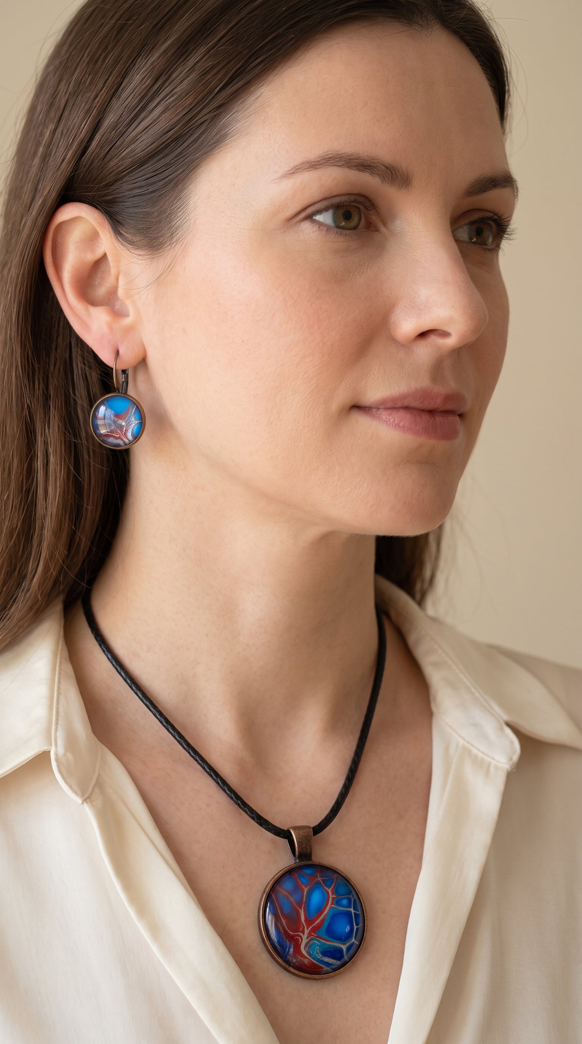 Frau trägt handgefertigtes Schmuckset Solas Autumn Blush mit Halskette und hängenden Ohrringen in Blau und Rot mit baumähnlichem abstraktem Kunstmotiv.