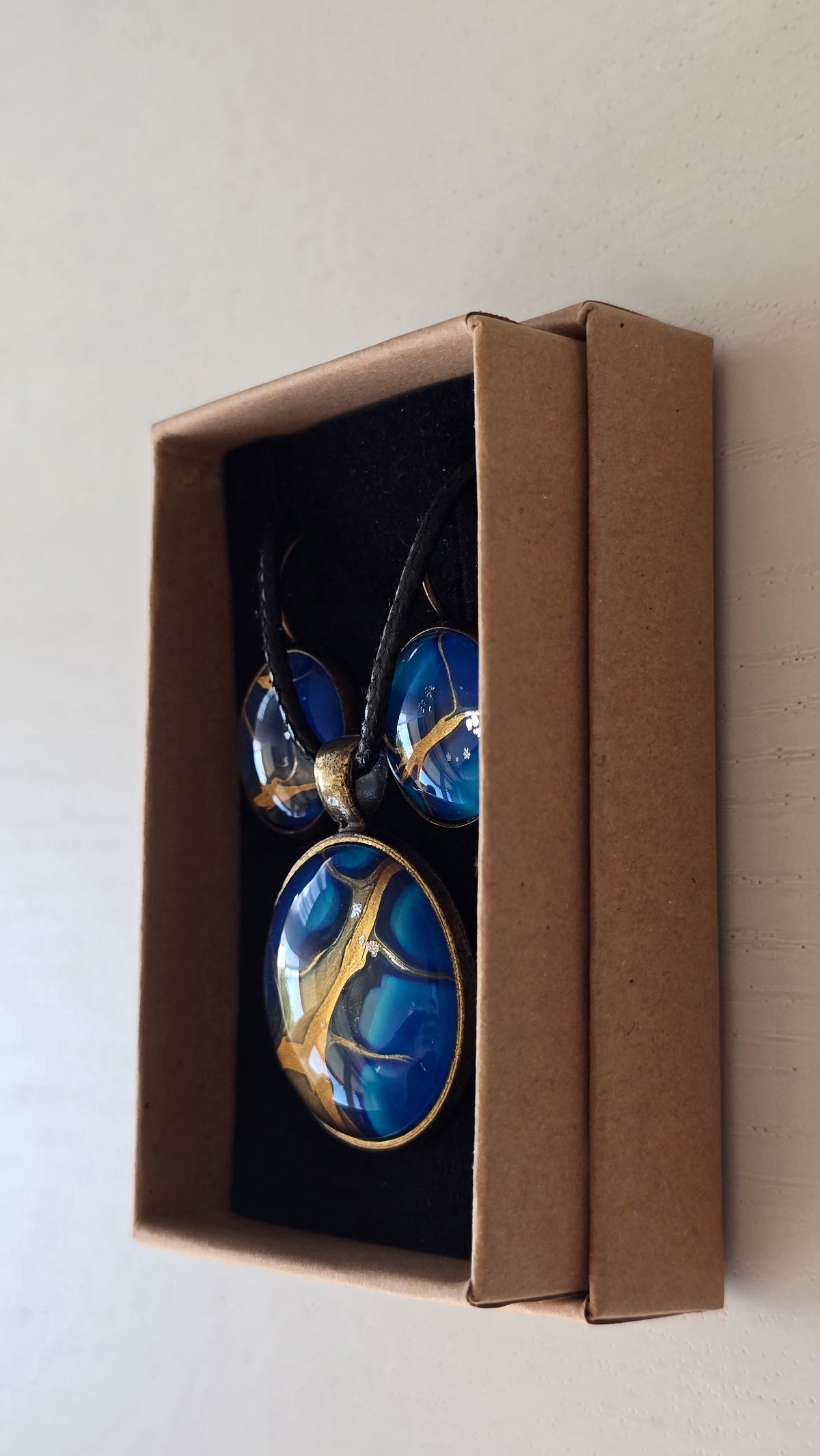 Handgefertigtes Schmuckset Solas Deep Current mit runder Halskette und passenden Ohrringen in tiefen Blau- und Goldtönen mit organischer Marmorierung.