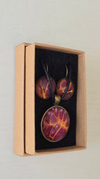 Handgefertigtes Schmuckset Solas Flare mit runder Halskette und passenden Ohrringen in Magenta-, Burgunder-, Orange- und Goldtönen mit leuchtender Marmorierung.