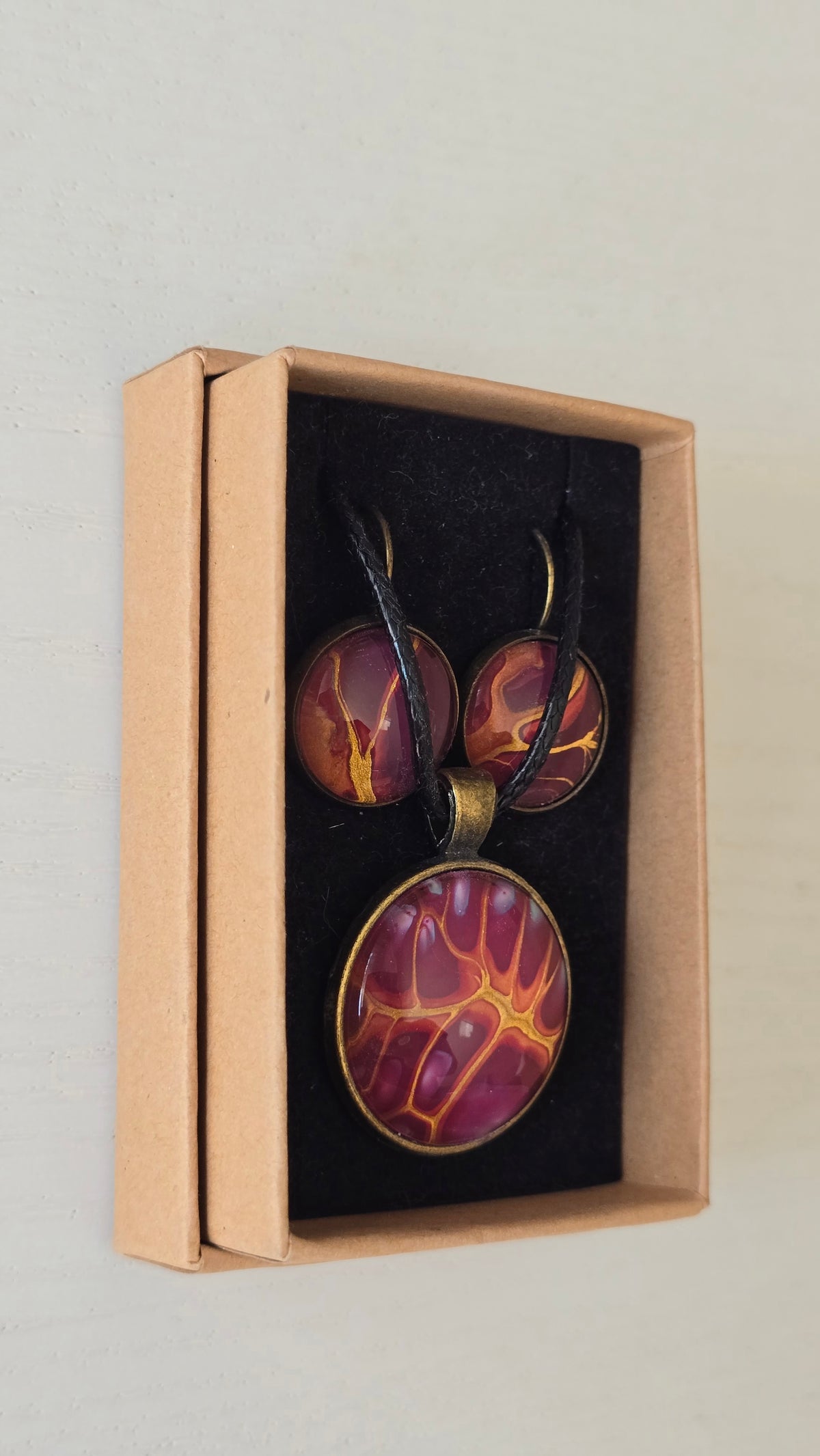 Handgefertigtes Schmuckset Solas Flare mit runder Halskette und passenden Ohrringen in Magenta-, Burgunder-, Orange- und Goldtönen mit leuchtender Marmorierung.