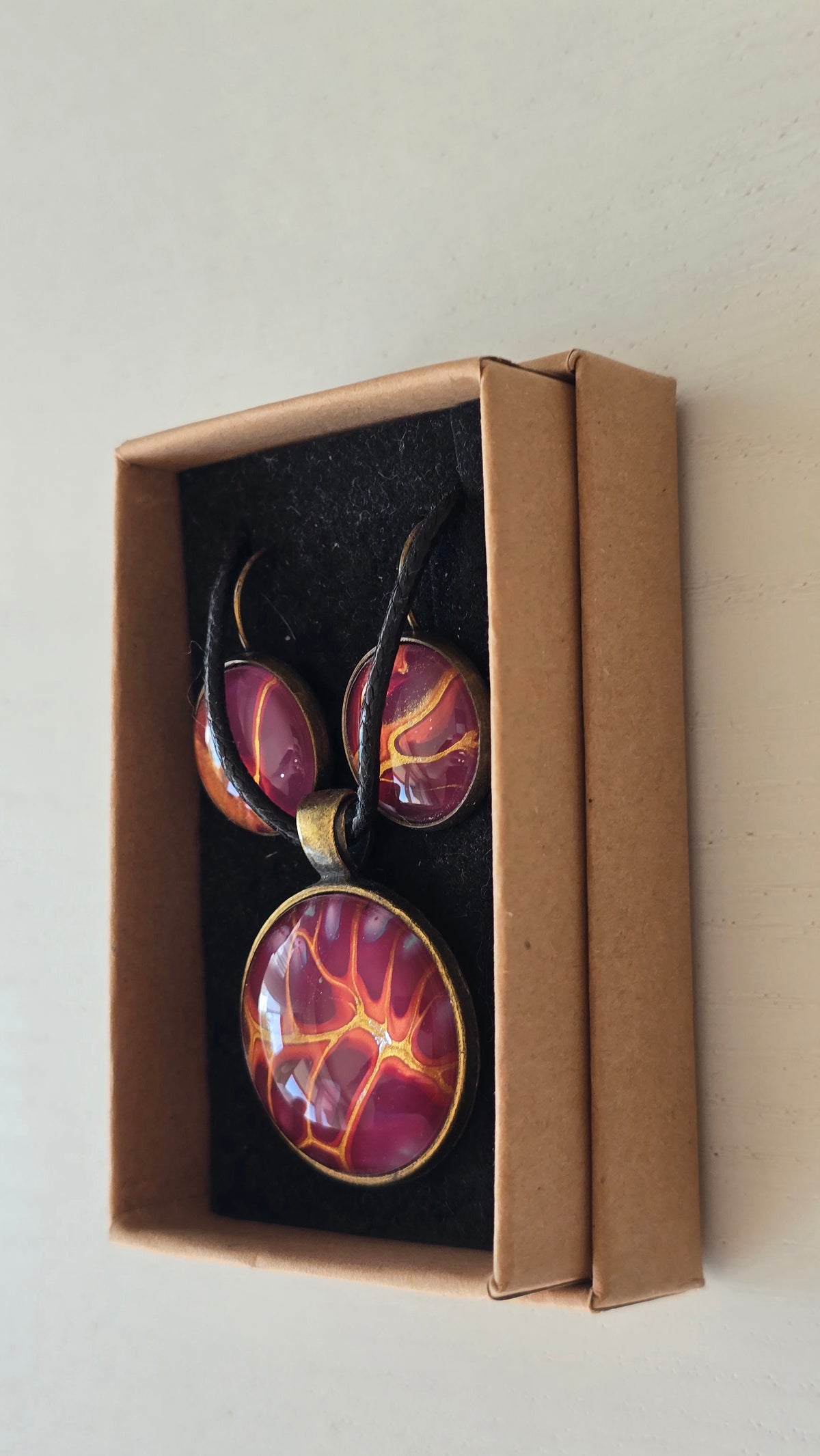Handgefertigtes Schmuckset Solas Flare mit runder Halskette und passenden Ohrringen in Magenta-, Burgunder-, Orange- und Goldtönen mit leuchtender Marmorierung.