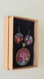 Handgefertigtes Schmuckset Solas Golden Spikes mit runder Halskette und passenden Ohrringen in Violett-, Türkis- und Goldtönen mit markanten goldenen Linien.