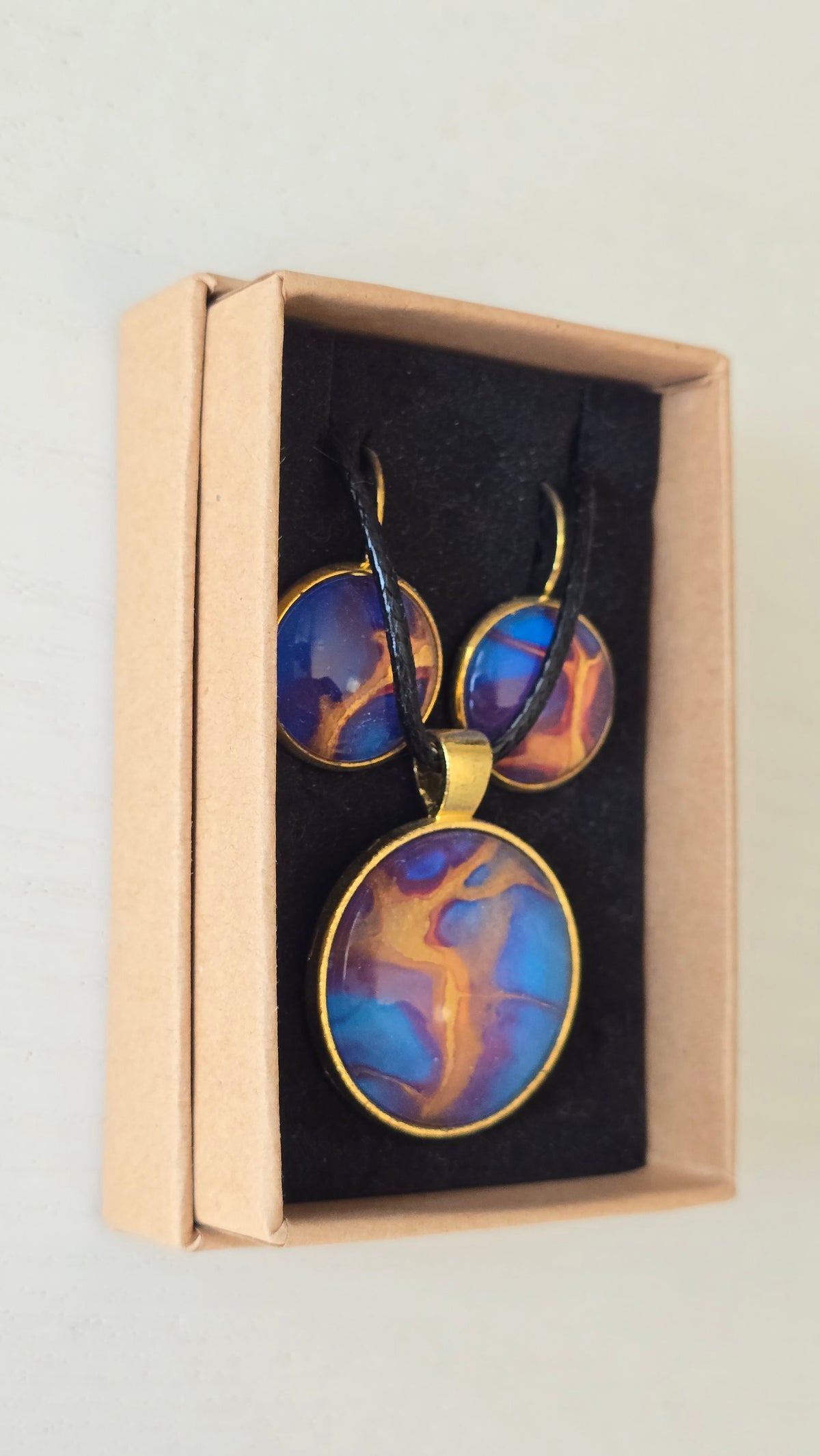 Handgefertigtes Schmuckset Solas Golden Dawn mit runder Halskette und passenden Ohrringen in Blau-, Violett- und Goldtönen mit fliessender Marmorierung.