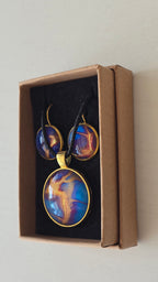 Handgefertigtes Schmuckset Solas Golden Dawn mit runder Halskette und passenden Ohrringen in Blau-, Violett- und Goldtönen mit fliessender Marmorierung.