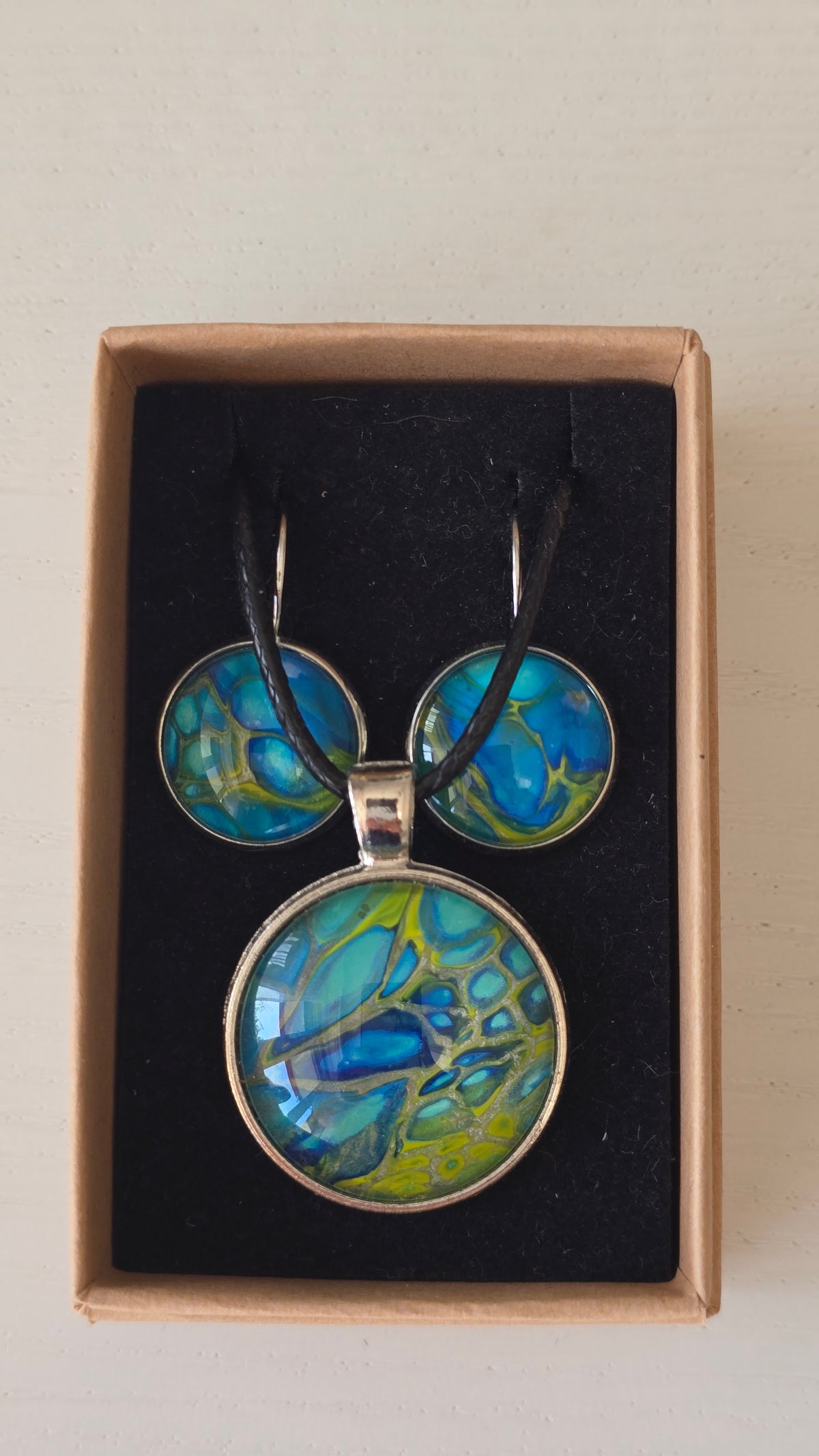 Handgefertigtes Schmuckset Solas Green Horizon mit runder Halskette und passenden Ohrringen in Blau-, Türkis- und Grüntönen mit organischer Marmorierung.