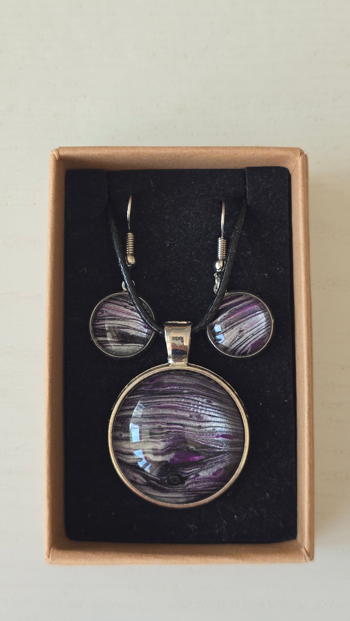 Handgefertigtes Schmuckset Solas Purple Sands mit runder Halskette und passenden Ohrringen in Violett-, Flieder- und Silbertönen mit feiner, sandähnlicher Linienstruktur.