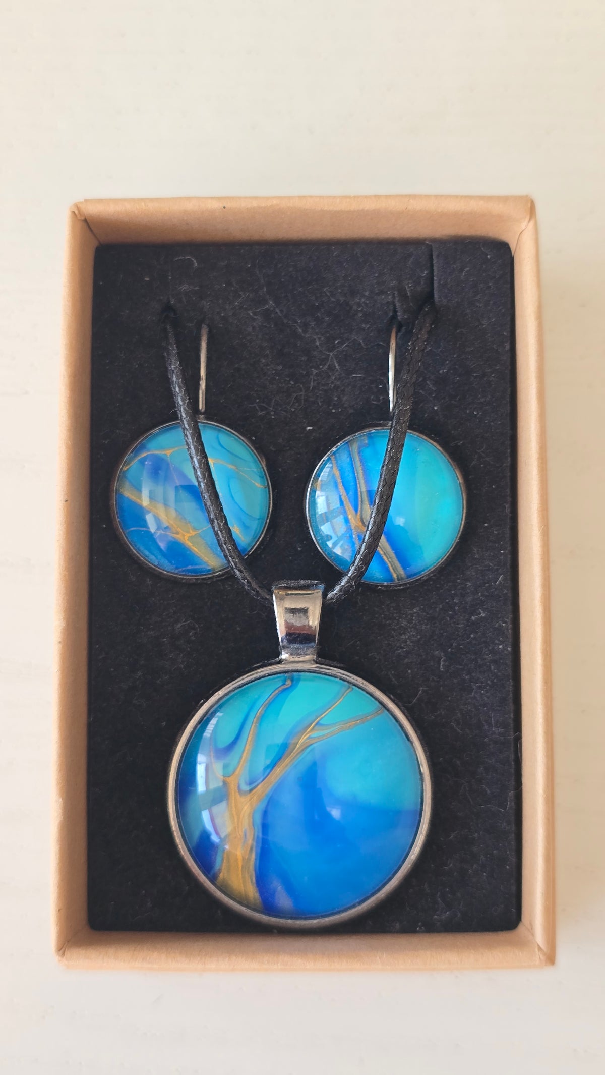 Handgefertigtes Schmuckset Solas Tide mit runder Halskette und passenden Ohrringen in Türkis-, Blau- und goldenen Farbtönen mit fließender Marmorierung.