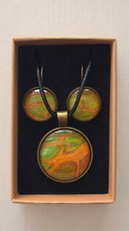 Rundes Cabochon Schmuckset mit grossem Kettenanhänger und zwei passenden Ohrringen in Grün, Orange und Gold mit fliessenden, organischen Mustern, bronzefarbenen Fassungen und schwarzem Band.