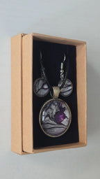 Cabochon-Schmuckset mit rundem Anhänger und zwei Ohrringen in schimmerndem Silber und Grau mit dunklen marmorierten Adern und violettem Farbkern.