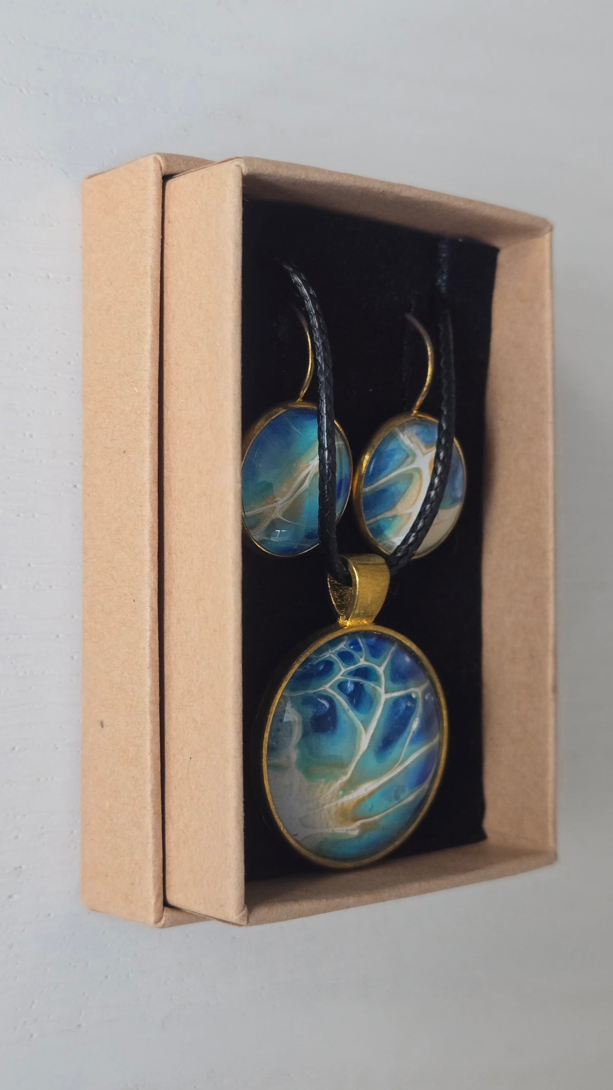 Rundes Cabochon-Schmuckset mit grossem Halskettenanhänger und zwei passenden Ohrringen in Türkis, Blau und Creme mit feinen goldenen Akzenten.