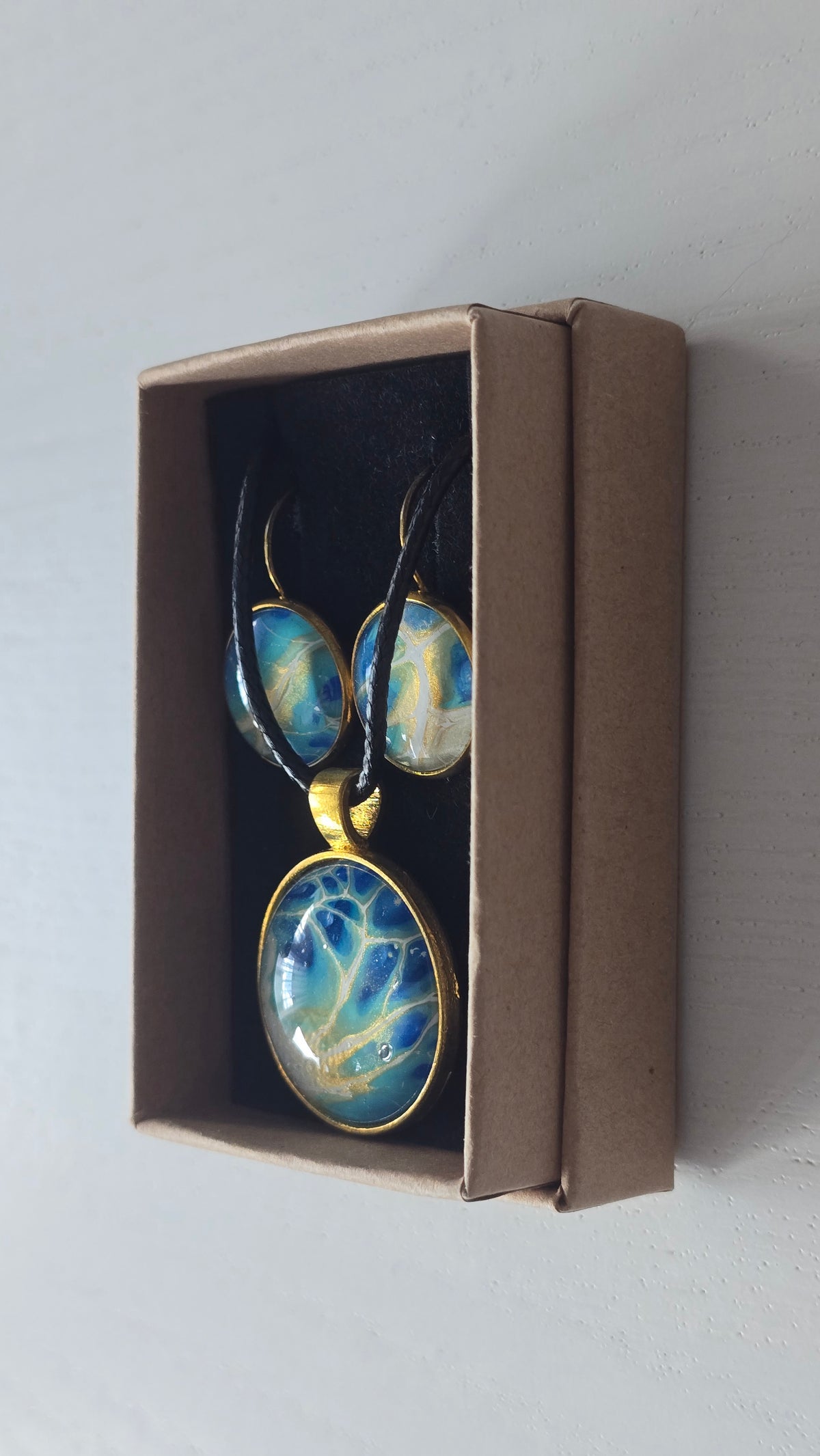 Rundes Cabochon-Schmuckset mit grossem Halskettenanhänger und zwei passenden Ohrringen in Türkis, Blau und Creme mit feinen goldenen Akzenten.