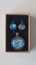 Rundes Cabochon-Schmuckset mit Anhänger und Ohrringen an schwarzem Band, mit fliessendem abstraktem Muster in Cyan, Blau, Grau und Schwarz.