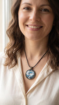 Frau trägt runde Cabochon-Kette mit fliessendem Muster in Silber, Anthrazit, Eisblau und Türkis in dunkler Metallfassung.
