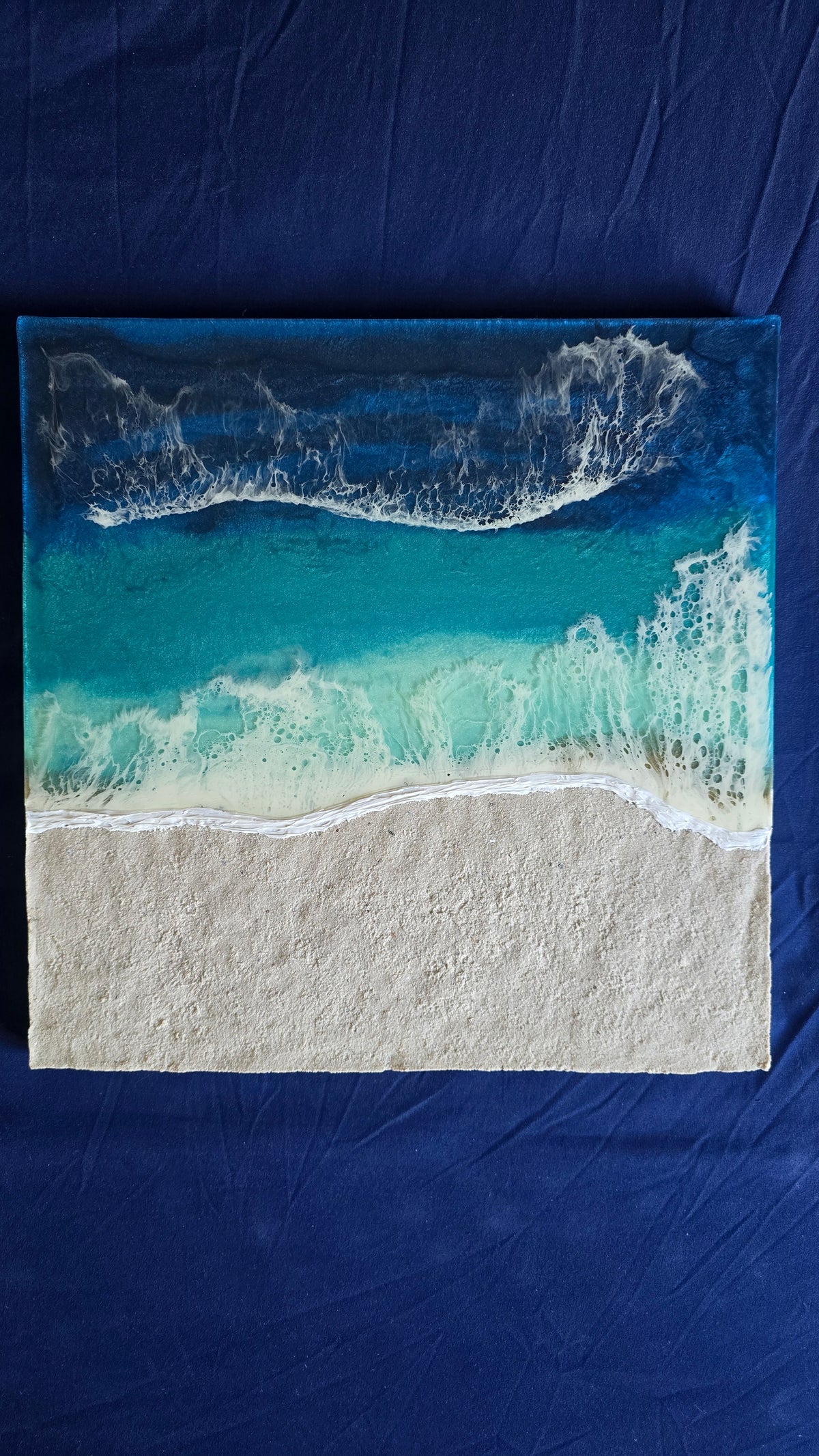 Handgefertigtes quadratisches resin gessobild mit türkisblauem Meer, weissen Wellen und strukturierter Sandfläche. Modernes Meeresbild als Unikat von Solas Artwork.