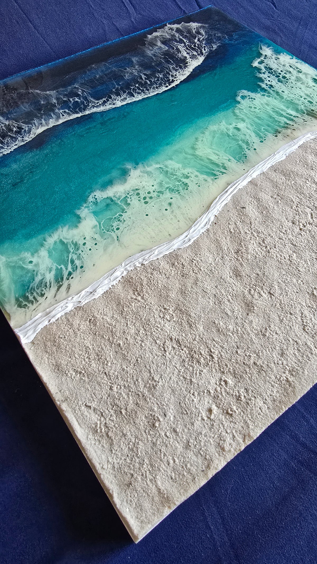 Handgefertigtes quadratisches resin gessobild mit türkisblauem Meer, weissen Wellen und strukturierter Sandfläche. Modernes Meeresbild als Unikat von Solas Artwork.