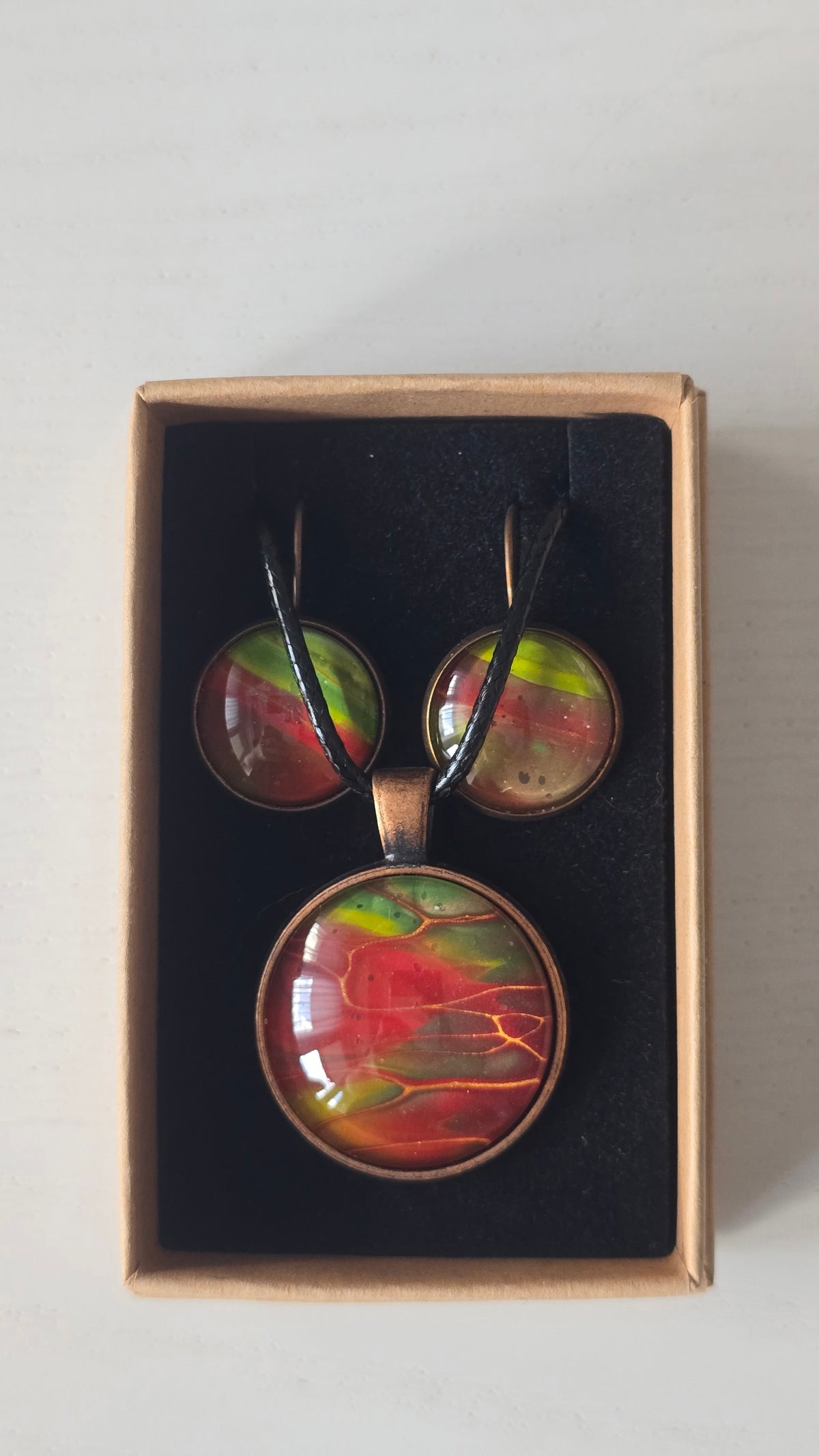 Rundes Cabochon-Schmuckset mit grossem Halskettenanhänger und zwei passenden Ohrringen in Rot, Grün und Gelb mit kupfer-goldenen Linien.