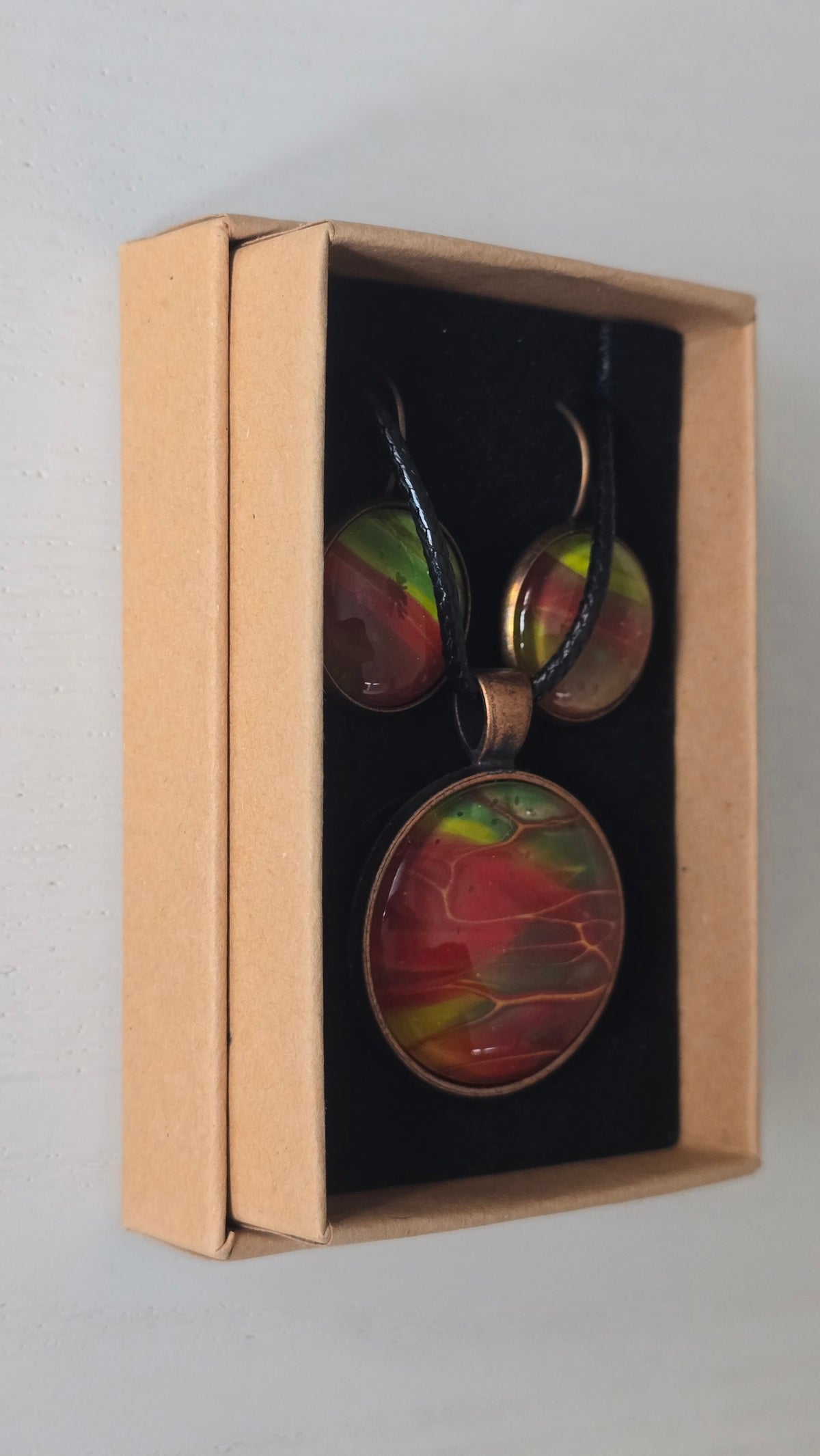 Rundes Cabochon-Schmuckset mit grossem Halskettenanhänger und zwei passenden Ohrringen in Rot, Grün und Gelb mit kupfer-goldenen Linien.