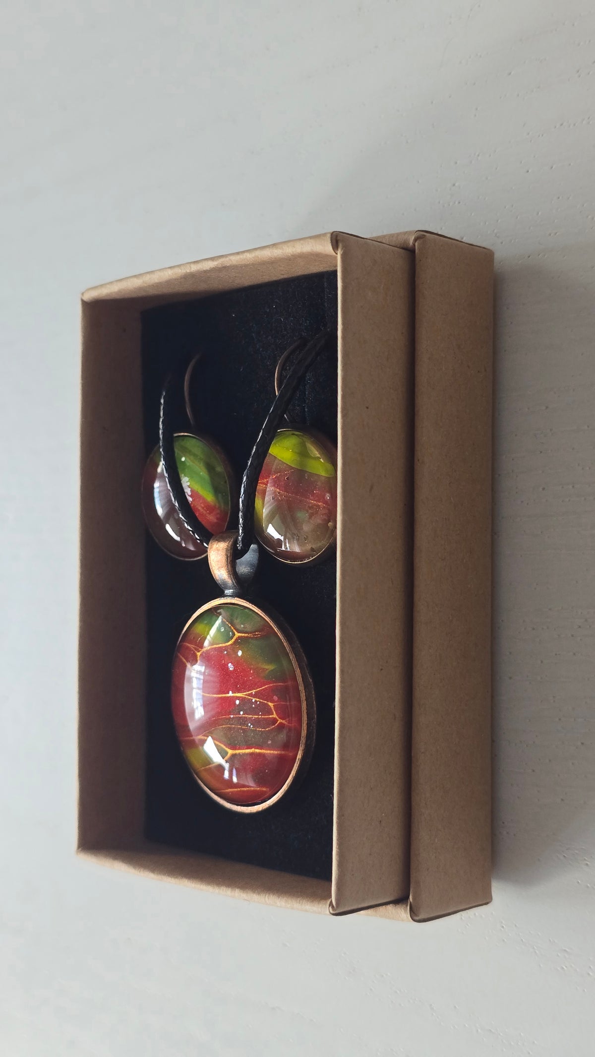 Rundes Cabochon-Schmuckset mit grossem Halskettenanhänger und zwei passenden Ohrringen in Rot, Grün und Gelb mit kupfer-goldenen Linien.
