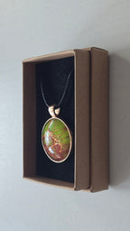 Runde Cabochon Kette Solas Bloom Temper mit leuchtend grüner, kupferroter Farbstruktur, bronzefarbener Fassung und schwarzem Band.