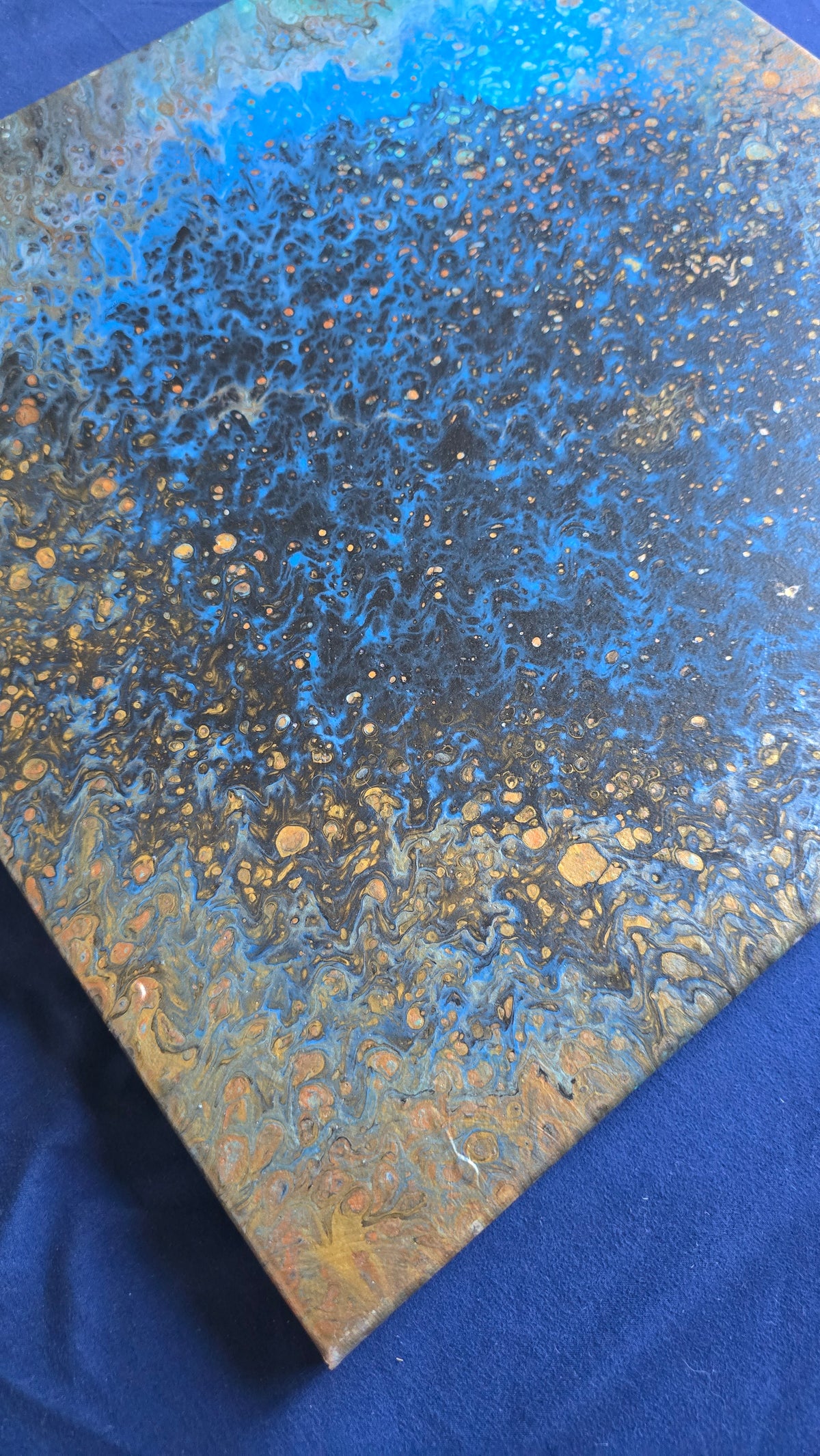 Quadratisches abstraktes Leinwandbild in intensivem Blau und Türkis mit dunklen Zellstrukturen sowie kleinen goldenen und erdigen Akzenten.