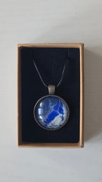 Runde Cabochon Kette Solas Blue Glacier in Kobaltblau, Silber und Weiss mit dunkler Metallfassung und schwarzem Band.