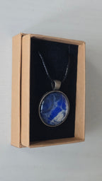 Runde Cabochon Kette Solas Blue Glacier in Kobaltblau, Silber und Weiss mit dunkler Metallfassung und schwarzem Band.