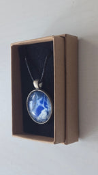Runde Cabochon Kette Solas Blue Glacier in Kobaltblau, Silber und Weiss mit dunkler Metallfassung und schwarzem Band.