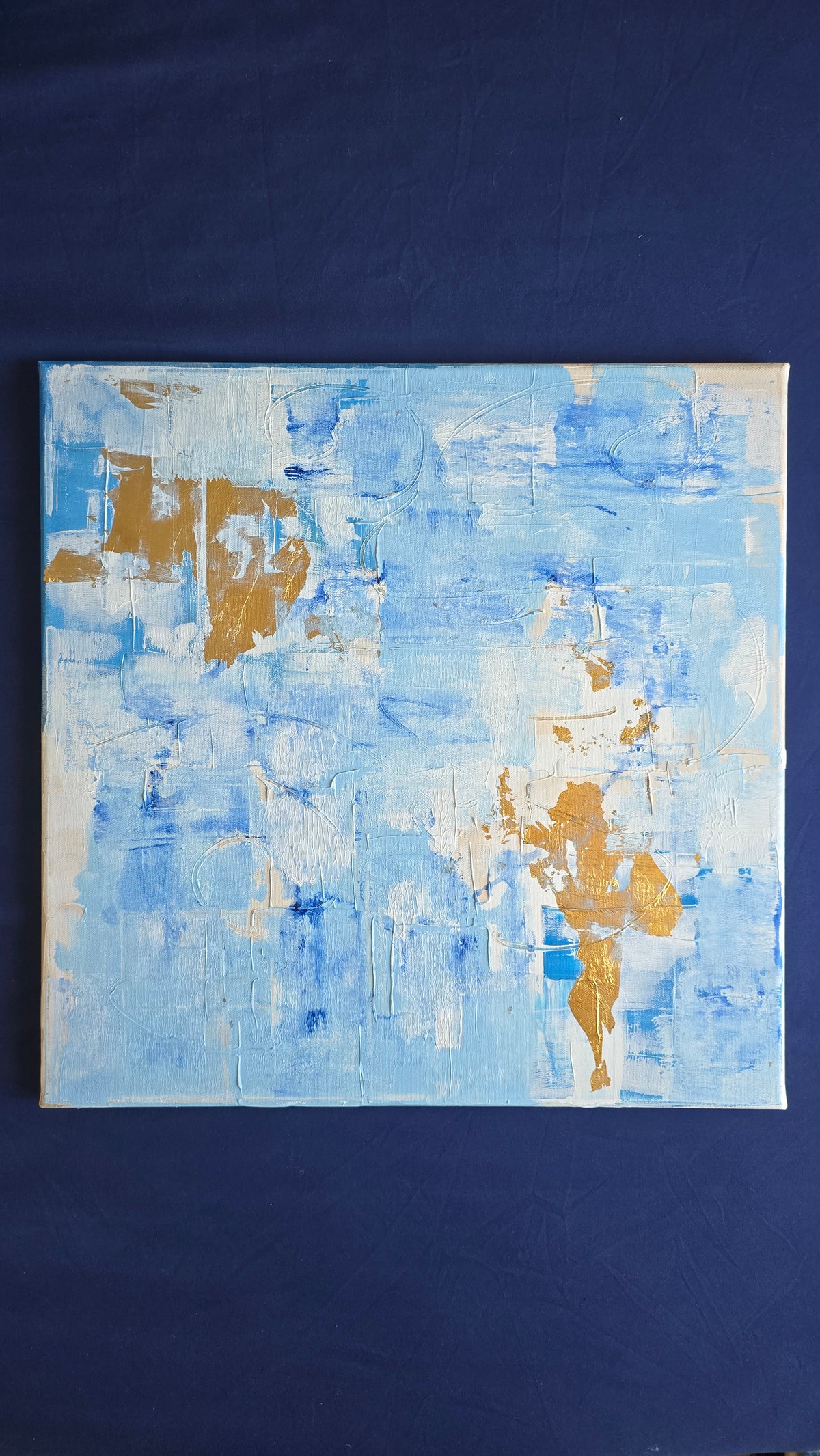 Quadratisches abstraktes Acryl-Leinwandbild mit strukturierten Farbflächen in Hellblau, Weiss, kräftigem Blau und goldenen Akzenten.