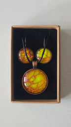 Rundes Cabochon-Schmuckset mit Anhänger und Ohrringen an schwarzem Band, mit organischem Muster in Gelb, Limettengrün und Orange, durchzogen von goldenen Adern.