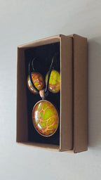 Rundes Cabochon-Schmuckset mit Anhänger und Ohrringen an schwarzem Band, mit organischem Muster in Gelb, Limettengrün und Orange, durchzogen von goldenen Adern.