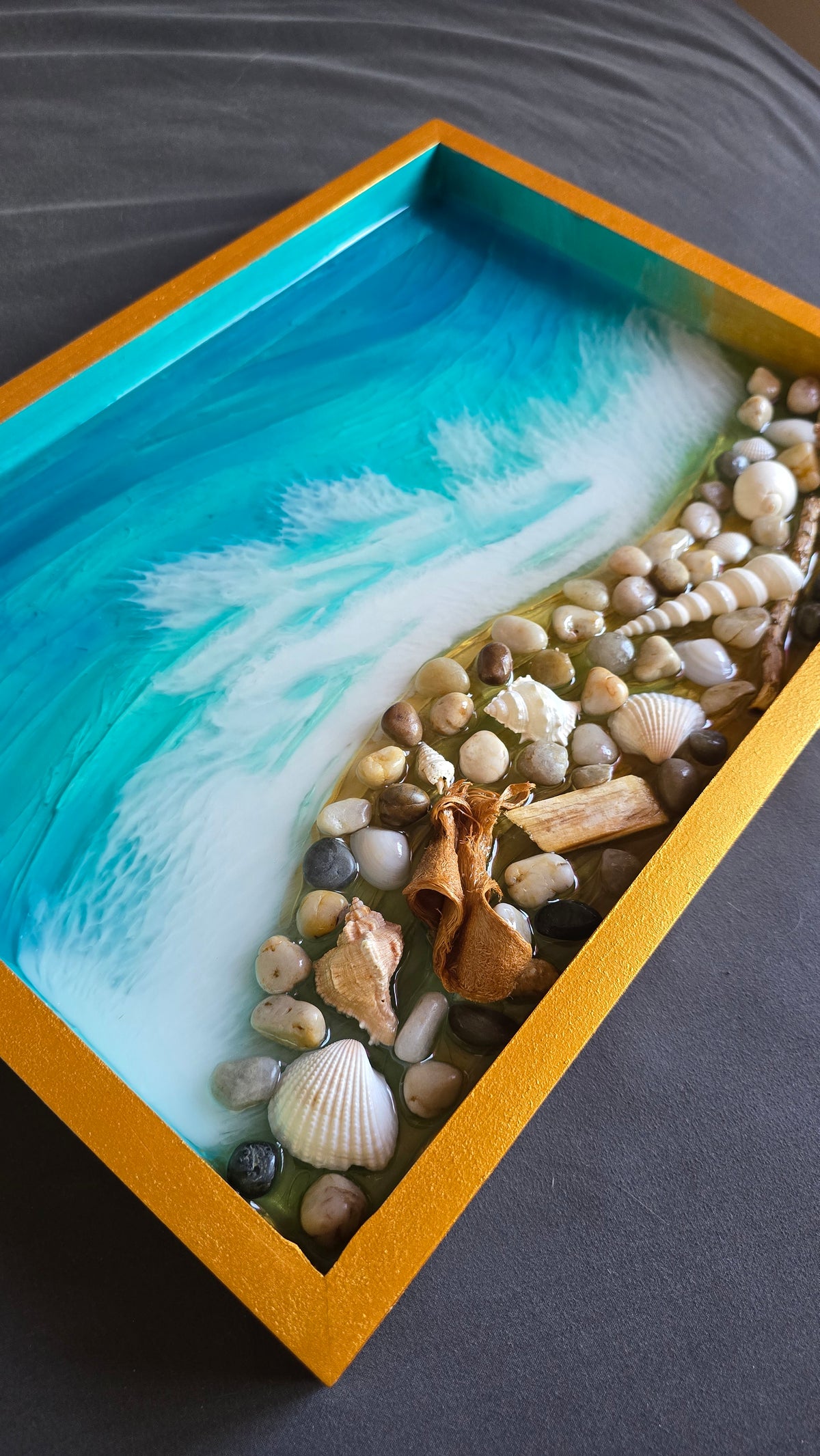 Handgefertigtes Resin-Kunstwerk «Solas Coastal Treasures» mit türkisfarbenem Meer, schäumenden Wellen, echten Muscheln, Steinen und Treibholz in einem goldenen Rahmen, 40 × 30 cm.