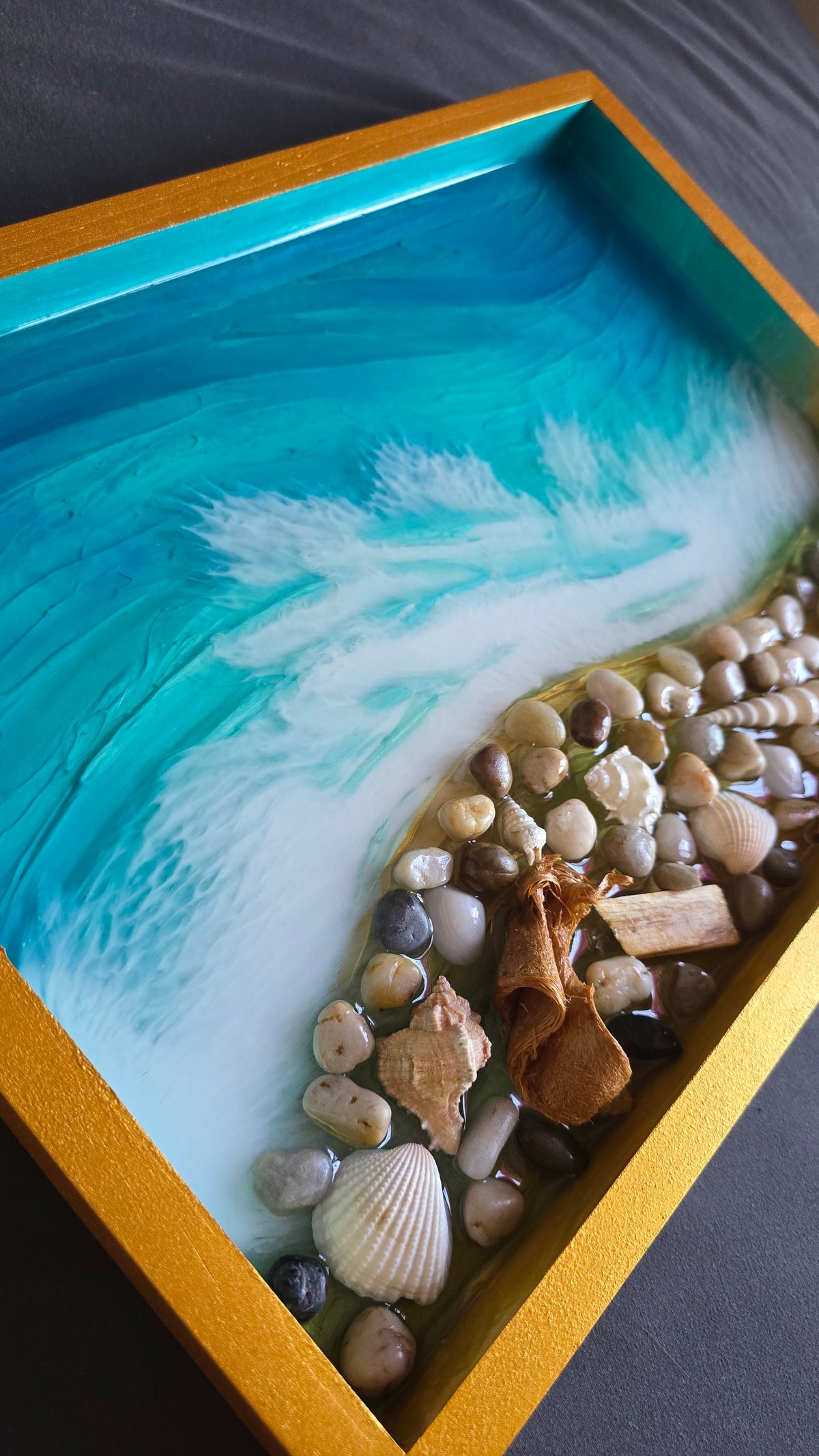 Handgefertigtes Resin-Kunstwerk «Solas Coastal Treasures» mit türkisfarbenem Meer, schäumenden Wellen, echten Muscheln, Steinen und Treibholz in einem goldenen Rahmen, 40 × 30 cm.