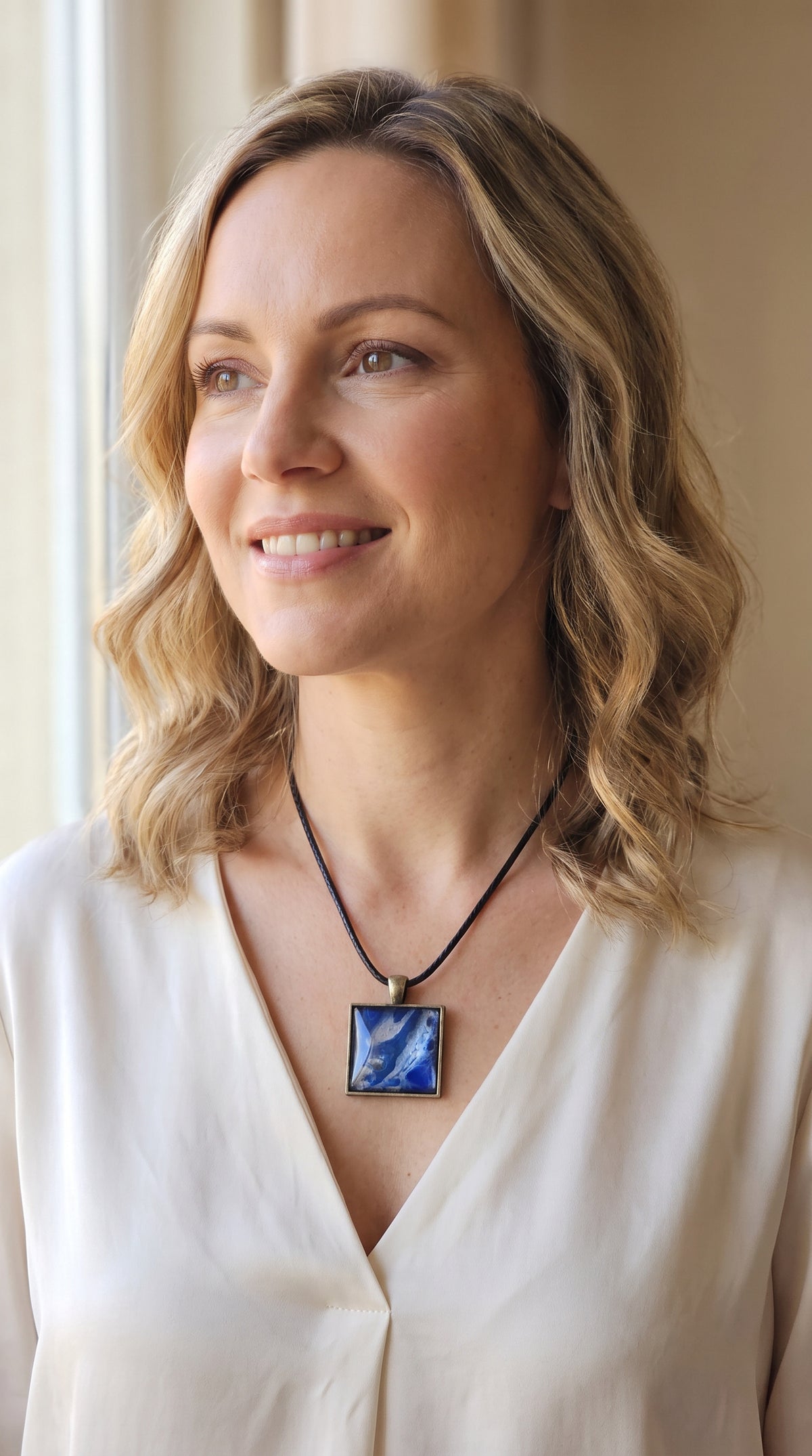 Frau trägt quadratische Cabochon-Kette mit fliessendem Muster in intensivem Kobaltblau und metallisch schimmerndem Silber.