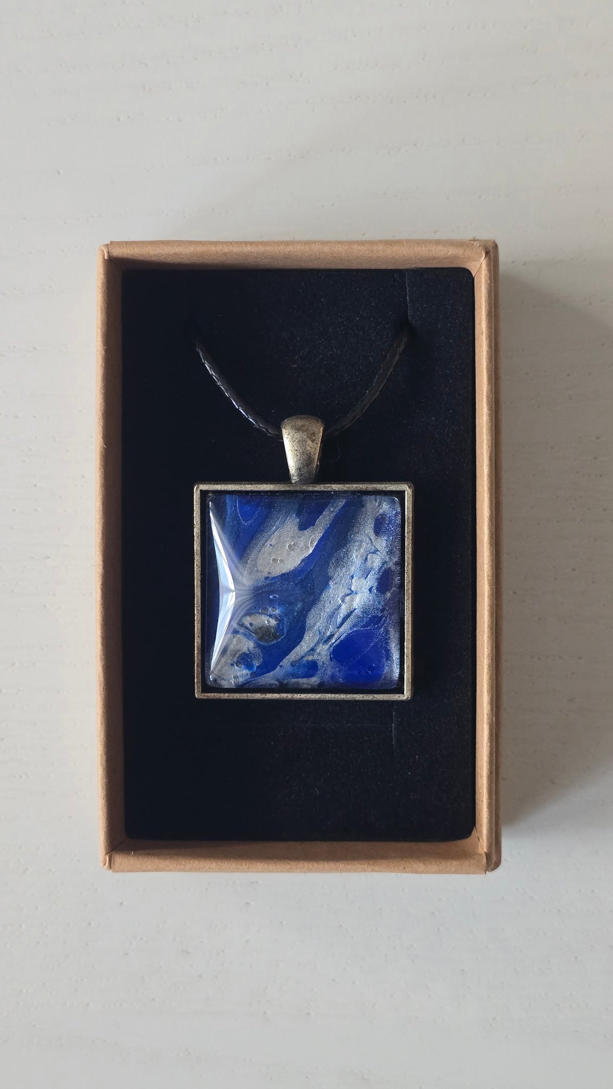 Quadratische Cabochon-Kette mit fliessendem Muster in intensivem Kobaltblau und metallisch schimmerndem Silber.