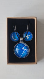 Rundes Cabochon-Schmuckset mit Anhänger und Ohrringen an schwarzem Band, mit organischem Inselmuster in Kobaltblau, Azurblau, Cyan und hellen Linien.