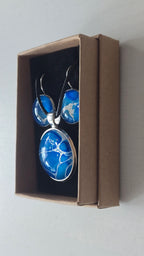 Rundes Cabochon-Schmuckset mit Anhänger und Ohrringen an schwarzem Band, mit organischem Inselmuster in Kobaltblau, Azurblau, Cyan und hellen Linien.