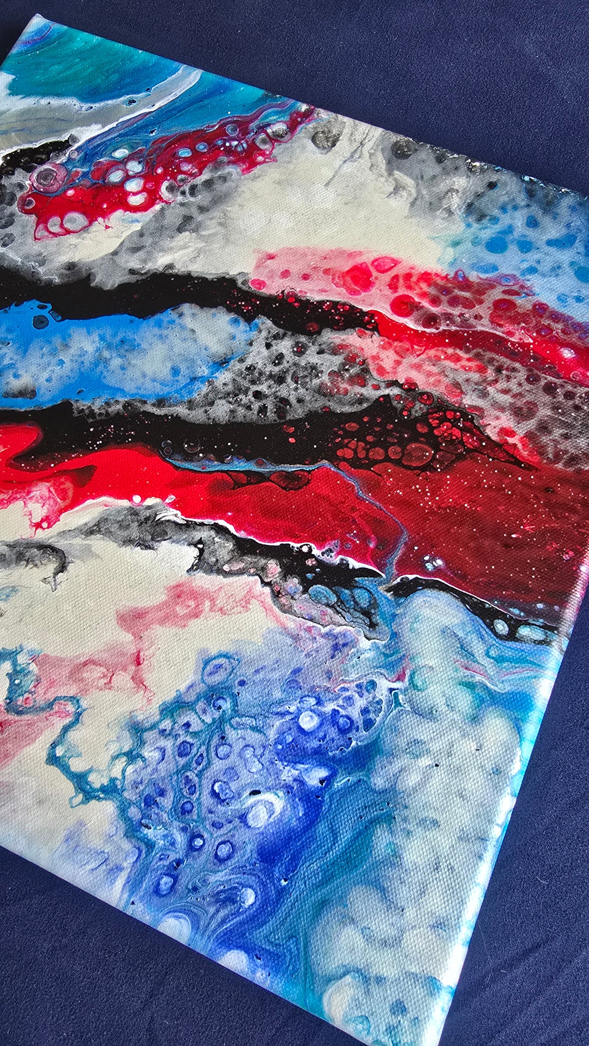 Quadratisches abstraktes Leinwandbild mit fliessenden roten, blauen, schwarzen, weissen und grauen Farbflächen und feinen Zellstrukturen.