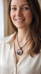 Frau trägt runde Cabochon-Kette mit abstrakten Strukturen in schimmerndem Kupfer, Schwarz, Anthrazit und Silber in dunkler Metallfassung.