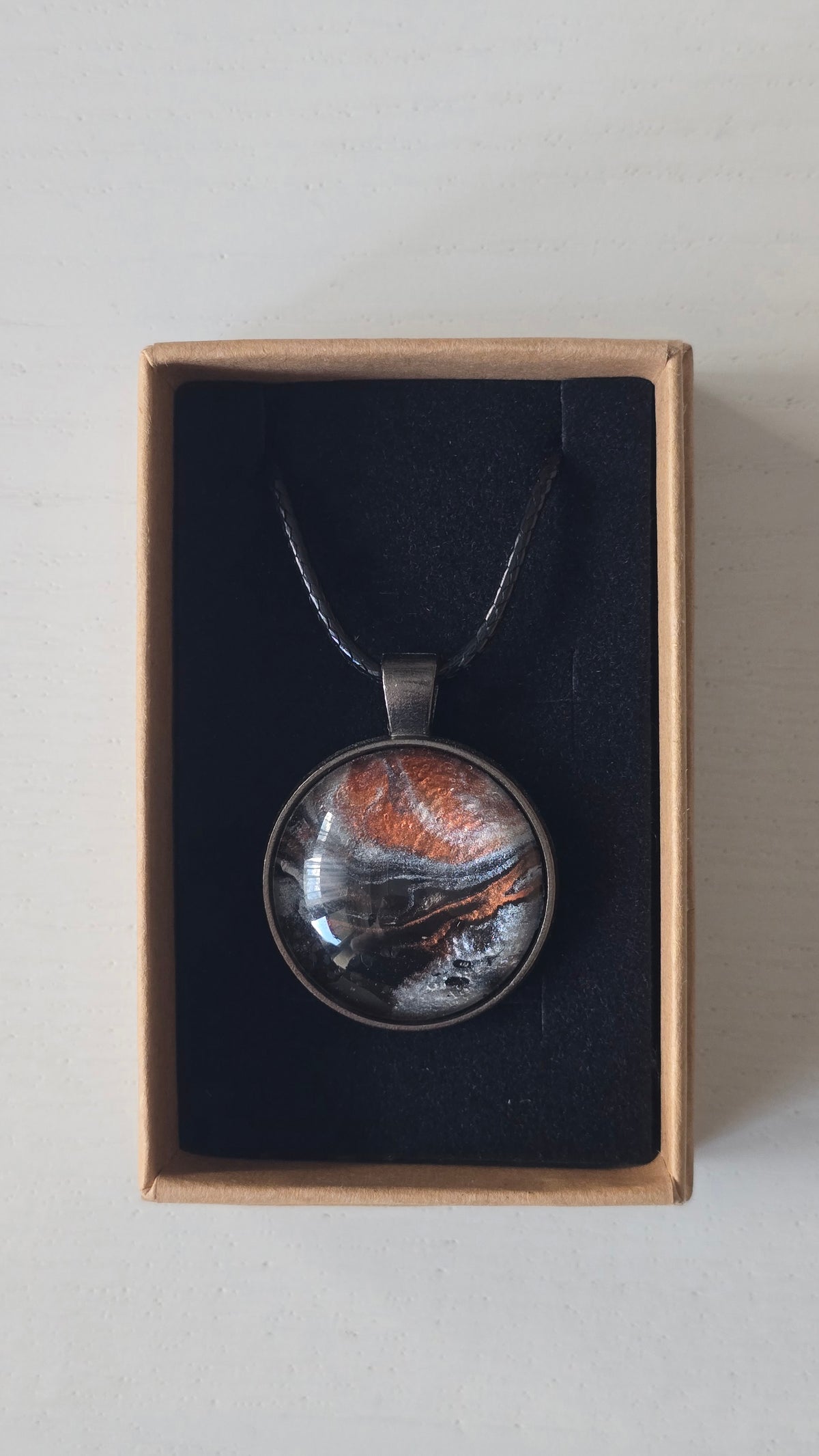 Runde Cabochon-Kette mit abstrakten Strukturen in schimmerndem Kupfer, Schwarz, Anthrazit und Silber in dunkler Metallfassung.