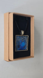 Quadratische Cabochon-Kette mit spiralförmigem, abstraktem Muster in intensivem Blau, Türkis und schimmerndem Silber.