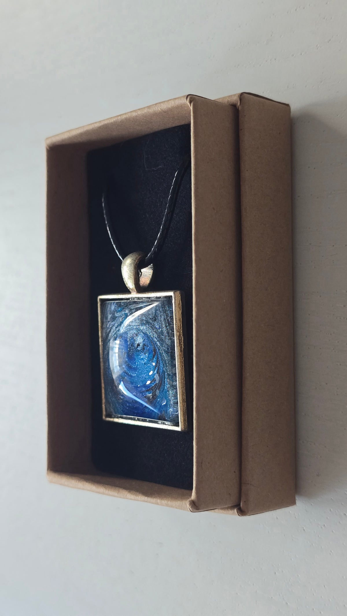 Quadratische Cabochon-Kette mit spiralförmigem, abstraktem Muster in intensivem Blau, Türkis und schimmerndem Silber.