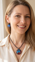 Frau trägt rundes Cabochon-Schmuckset mit Anhänger und Ohrringen an schwarzem Band, mit verzweigtem Muster in leuchtendem Cyan, Blau, Dunkelrot und Burgunder.