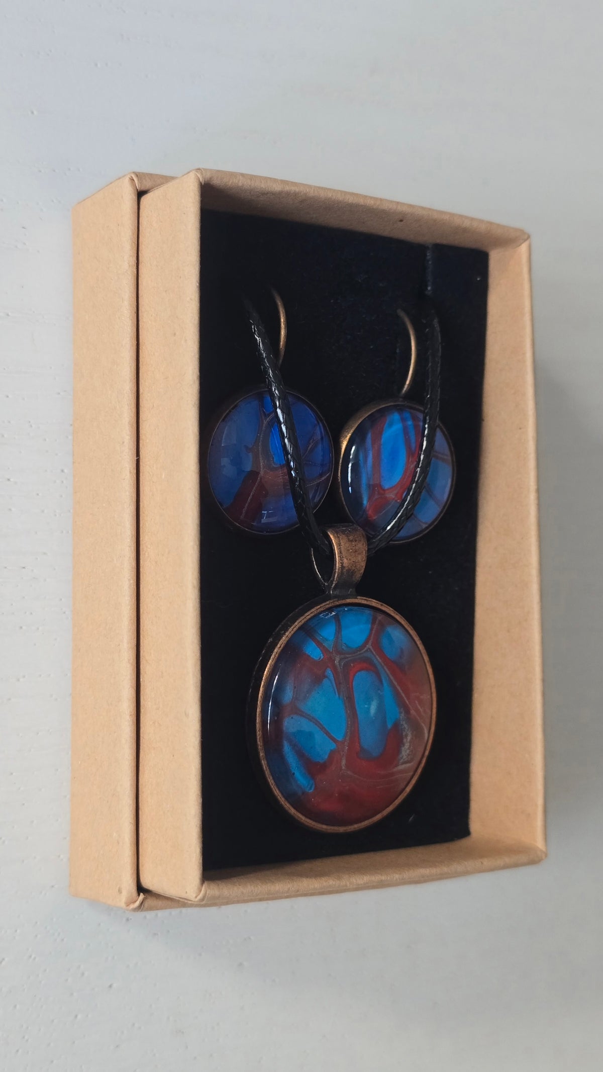 Rundes Cabochon-Schmuckset mit Anhänger und Ohrringen an schwarzem Band, mit verzweigtem Muster in leuchtendem Cyan, Blau, Dunkelrot und Burgunder.