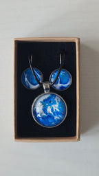 Cabochon Schmuckset Solas Crystal Wave mit runder Kette und passenden Ohrringen in leuchtendem Blau, Türkis und Weiss mit silberfarbenen Fassungen.