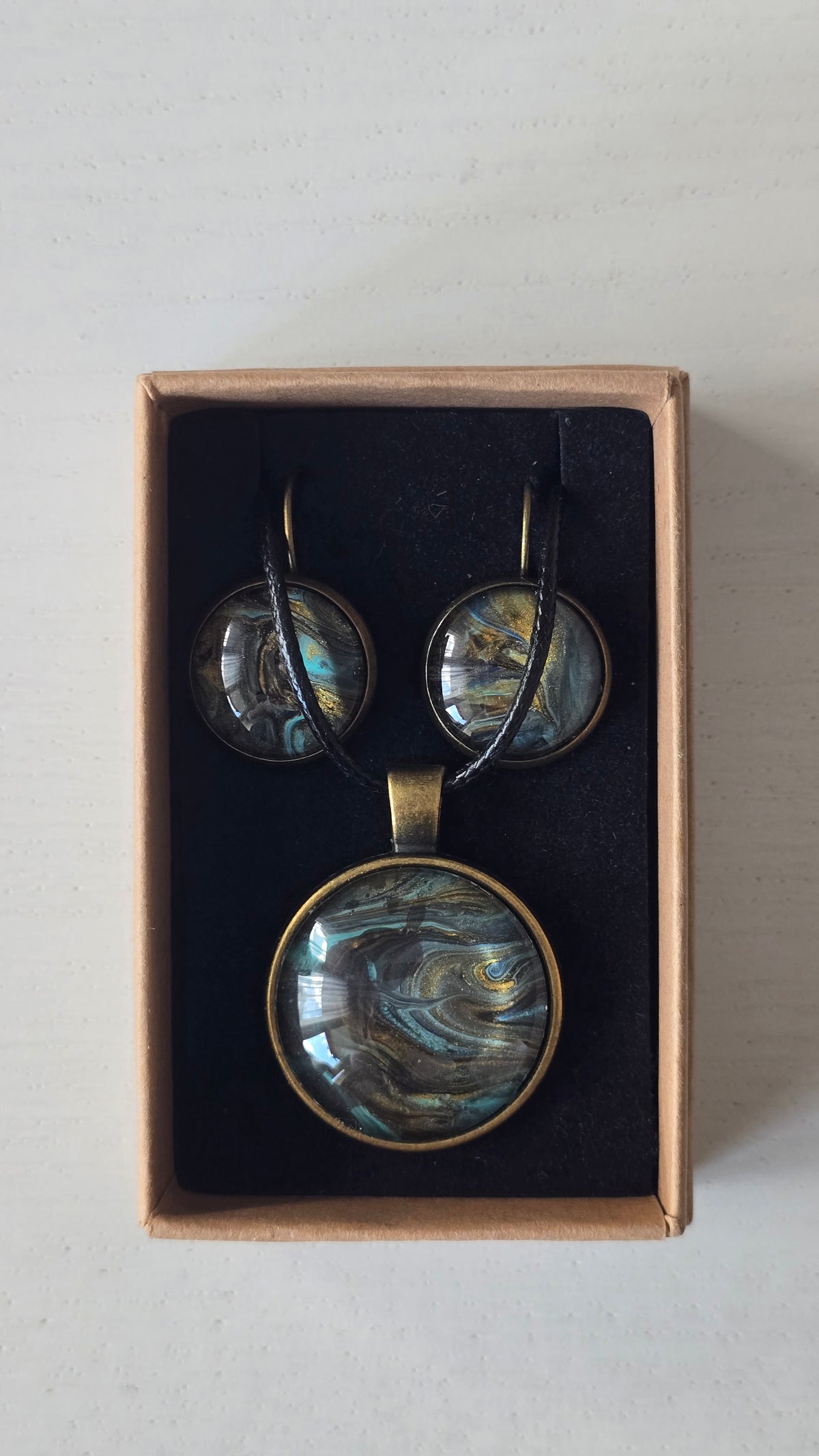 Rundes Cabochon Schmuckset mit Kette und zwei Ohrringen, abstraktes Muster in Schwarz, Türkis, Blaugrün und Gold mit fliessenden Strukturen.