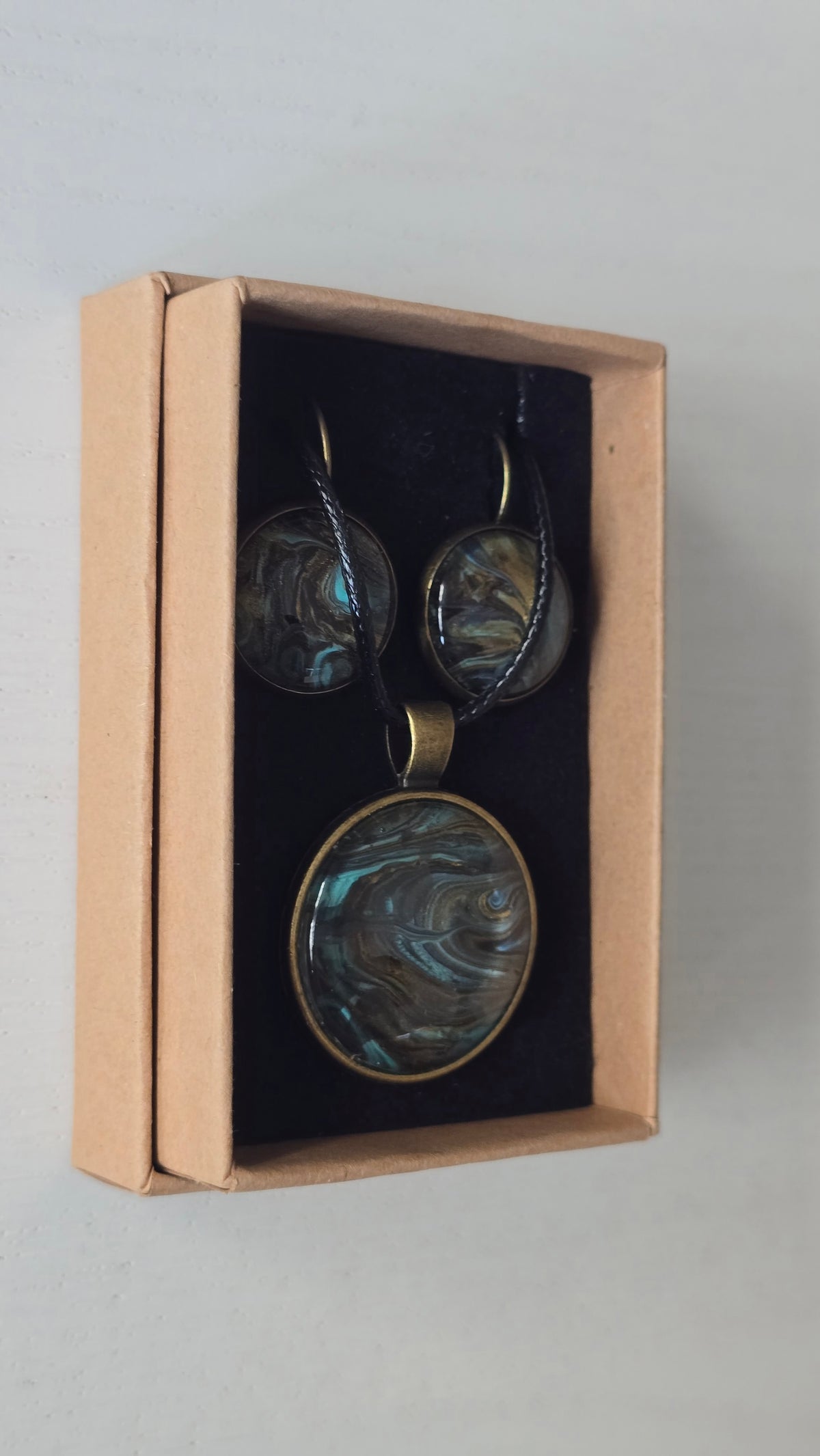 Rundes Cabochon Schmuckset mit Kette und zwei Ohrringen, abstraktes Muster in Schwarz, Türkis, Blaugrün und Gold mit fliessenden Strukturen.