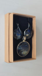 Rundes Cabochon-Schmuckset mit Anhänger und Ohrringen an schwarzem Band, mit fliessendem Muster in Dunkelblau, Schwarz und Petrol sowie goldenen Akzenten.
