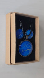 Rundes Cabochon-Schmuckset mit Anhänger und Ohrringen in intensivem Blau und Türkis, durchzogen von feinen silbernen Strukturen, an schwarzem geflochtenem Band.